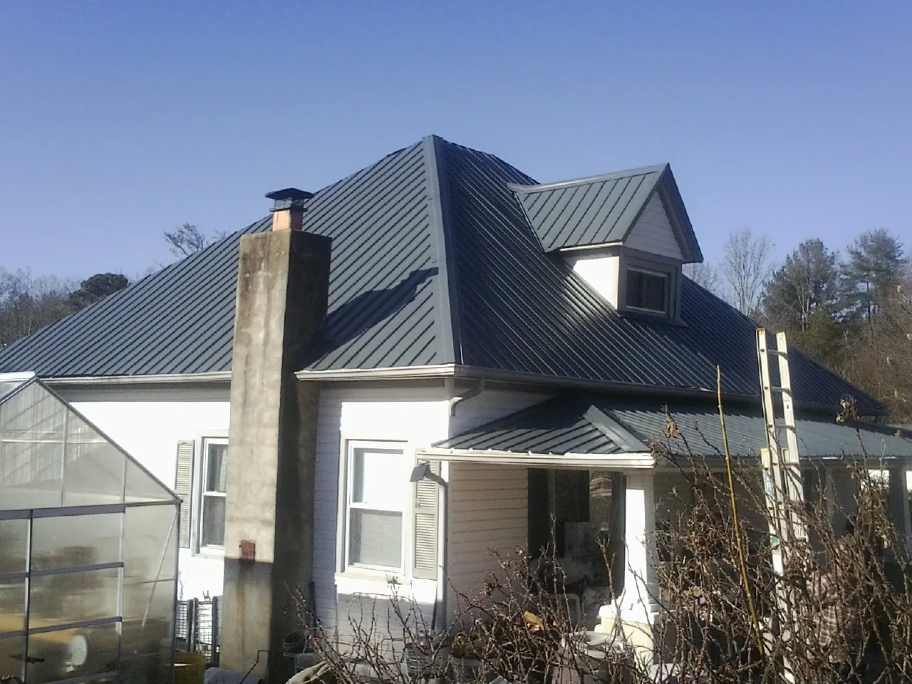 Dark blue standing seam metal roof on a white farmhouse with dormer — Slate & Tile Roof Repair by Roofing Brothers in Immaculata