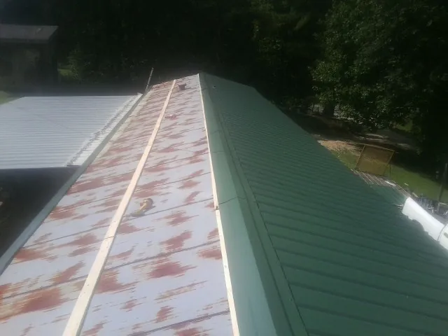 Old rusted panels beside newly installed green metal roofing — Wind Damage Roof Repair by Roofing Brothers in Immaculata