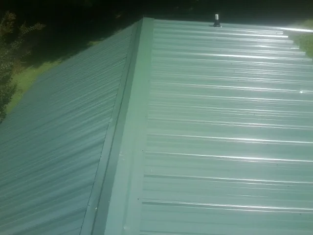 New green metal panels meeting at the ridge of a roof — Flat Roof Repair work by our crew in Immaculata