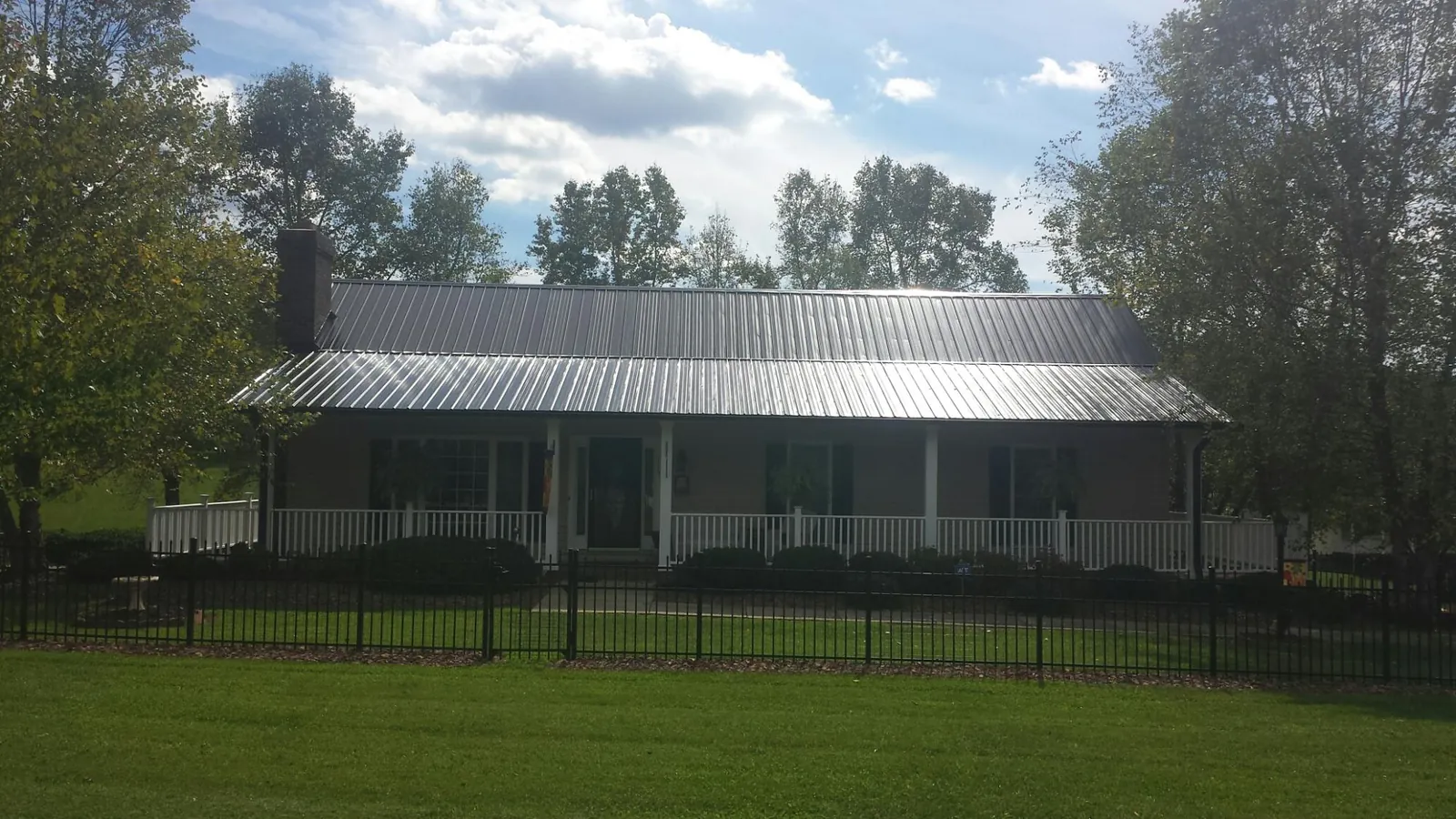 Gray metal roof on a brick ranch with a full width front porch — Gutter Guard Installation work by our crew in Immaculata