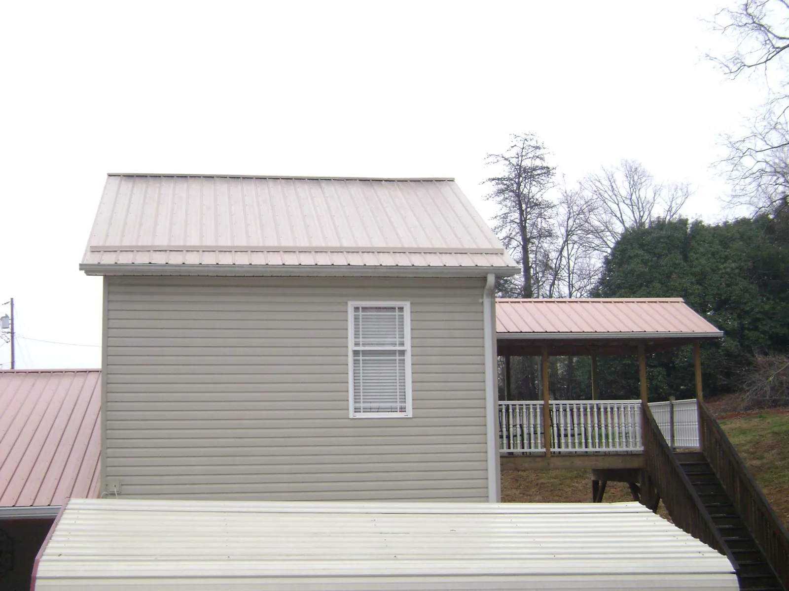Tan metal roofs on a two story addition and attached porch, from a Roof Replacement job in Immaculata