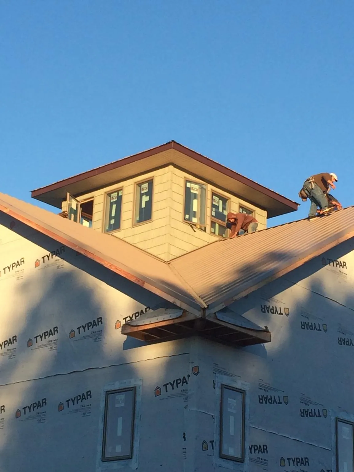Roofers working around a rooftop cupola on a new metal roof at sunset — Roof Waterproofing in Immaculata by Roofing Brothers